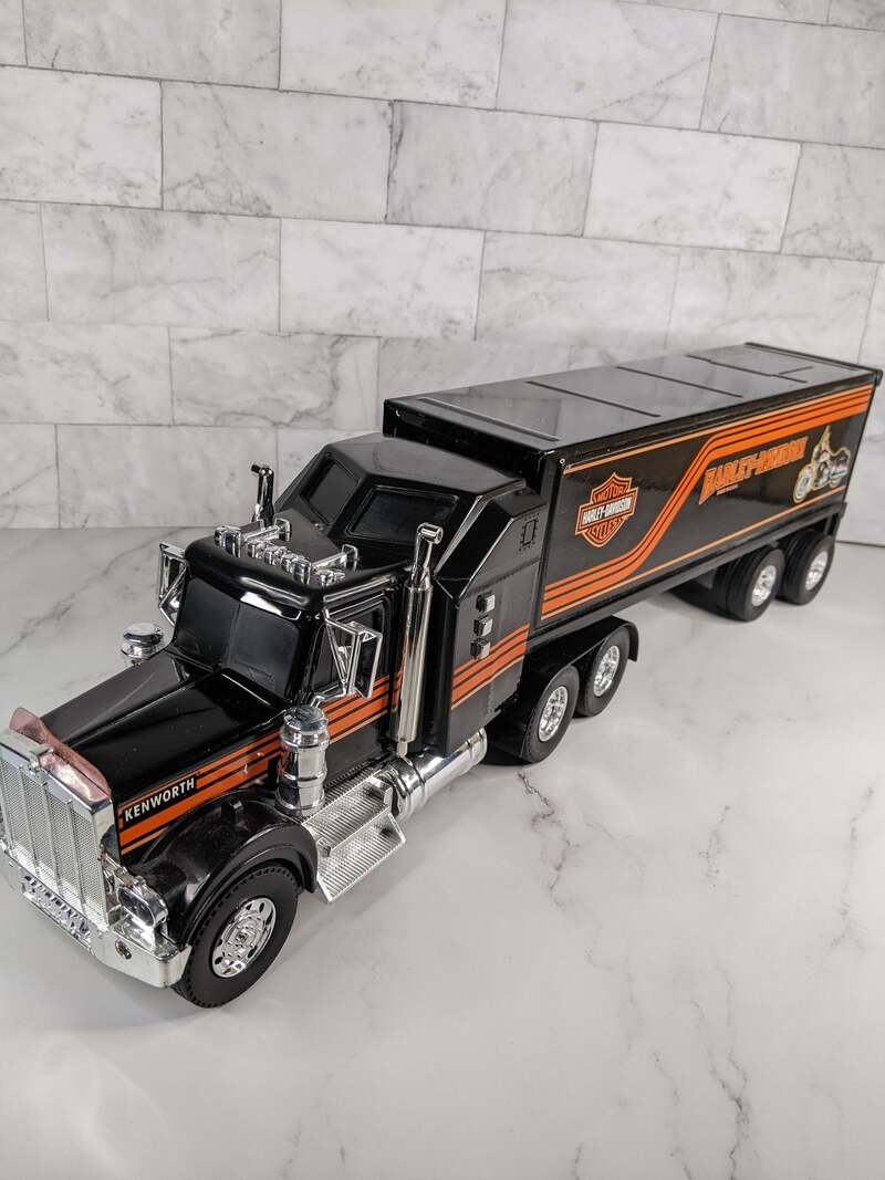 An Empire Kenworth Harley Davison semi-truck toy with lights and sounds, vintage from 1996, black and orange.