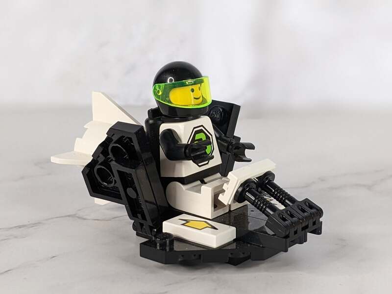 A vintage 1992 Lego figure, Blacktron 2 Galactic Scout 1426 1694 that is in a black and white space rocketship.