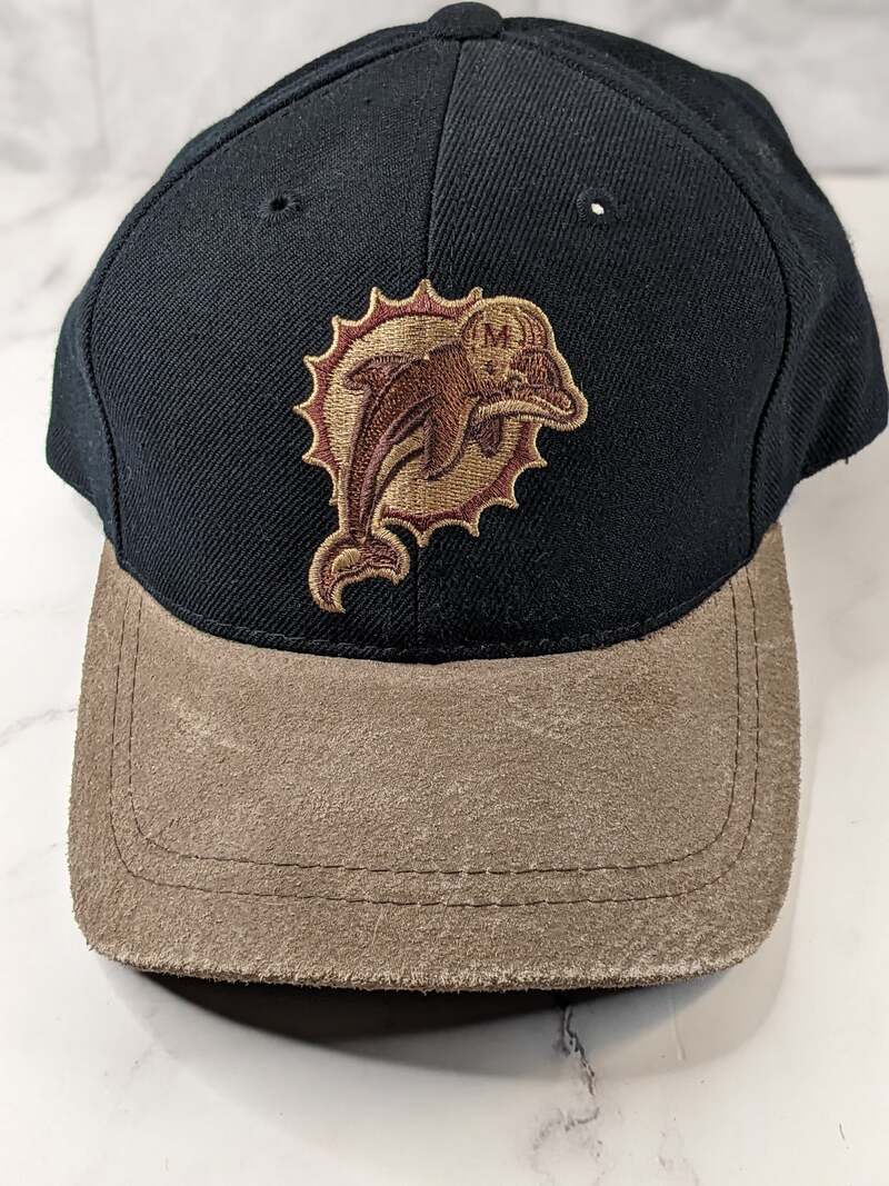 A black baseball-style cap with a tan bill and the vintage/retro NFL Miami Dolphins logo.