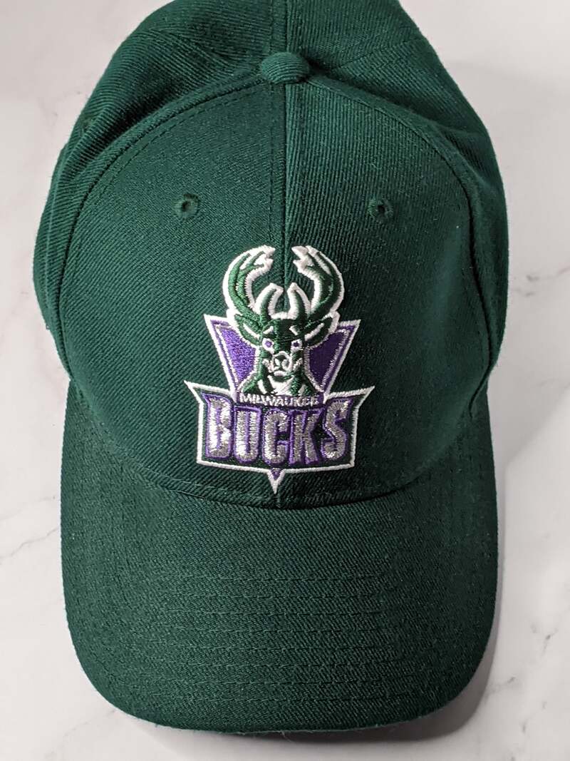 A green baseball cap with a purple deer vintage logo of the Milwaukee Bucks.